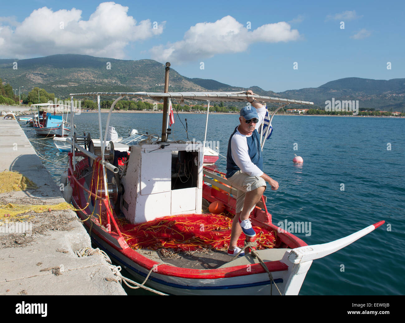 Voce maschile in posa sulla prua di un greco barca da pesca Foto Stock