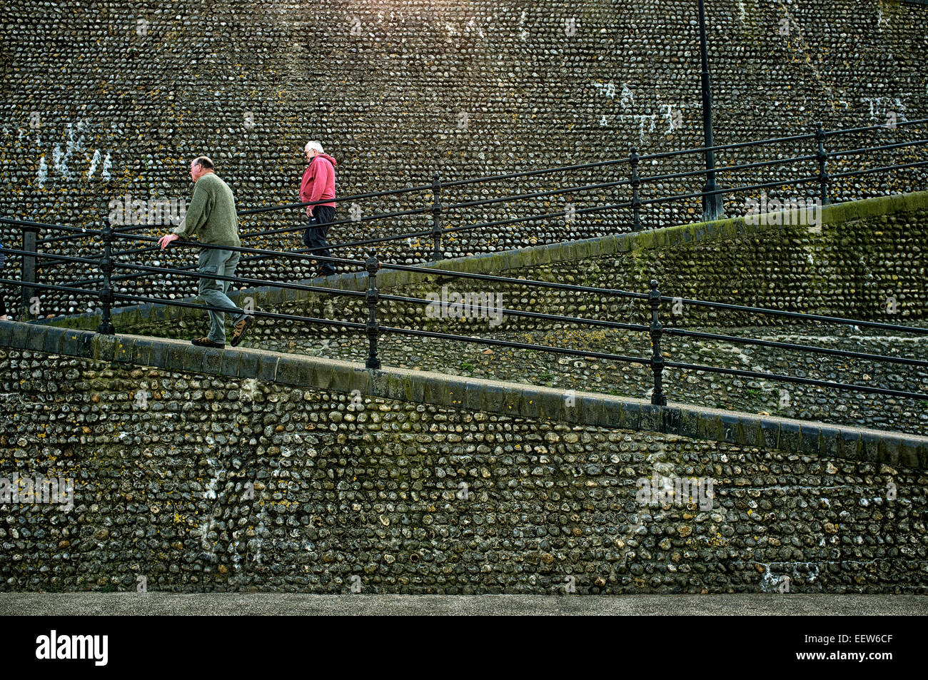 Due persone che camminano in direzioni diverse (su e giù) pendenza da Cromer lungomare in città. Foto Stock