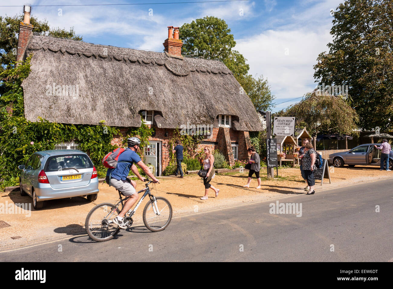 Ciclista passando cottage thatched hotel e ristorante, Brockenhurst, Hampshire, Inghilterra, GB, UK. Foto Stock