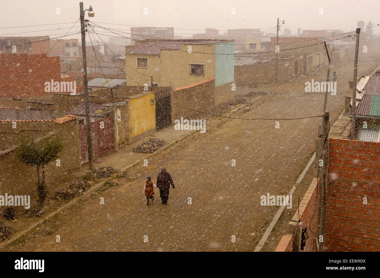 Le persone fanno la loro strada verso il basso un El Alto, Bolivia street come la neve comincia a cadere. Foto Stock