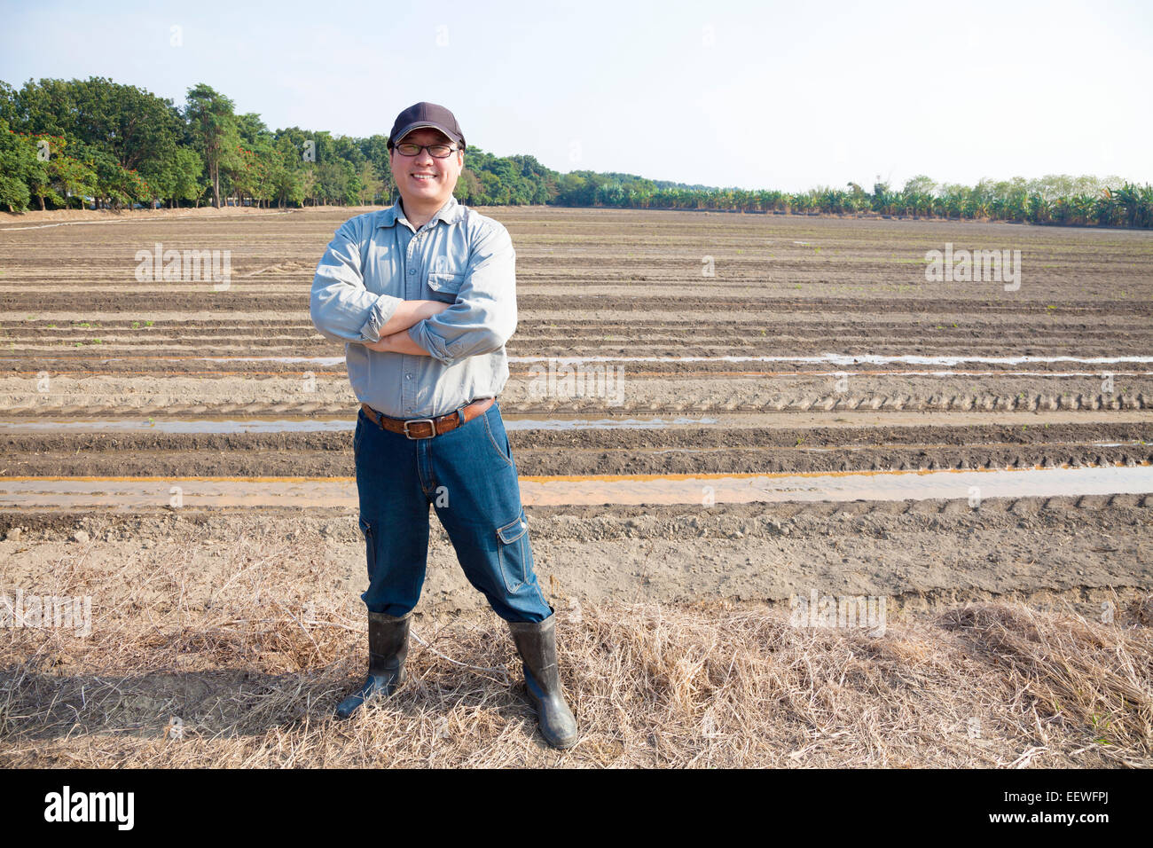 Asian agricoltore in piedi su terreni agricoli Foto Stock