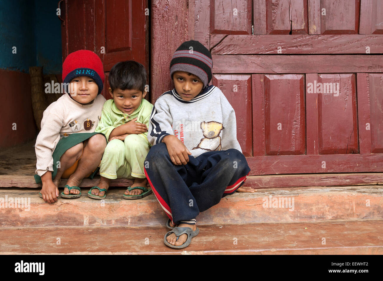 Bambini nepalesi seduto di fronte a una porta, Bandipur, Nepal Foto Stock