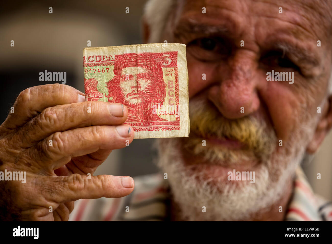 Anziani uomo cubano tenendo un 3 pesos a Bill con il ritratto di Ernesto Che Guevara in sua mano, Havana, Cuba Foto Stock
