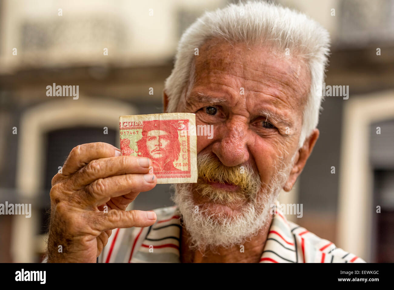 Anziani uomo cubano tenendo un 3 pesos a Bill con il ritratto di Ernesto Che Guevara in sua mano, Havana, Cuba Foto Stock