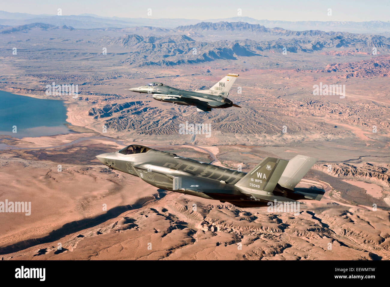 US Air Force F-35un fulmine II Stealth Fighter Aircraft e F-16 Fighting Falcon fighter approcciare il Lake Mead National Recreation Area in itinerario alla Nellis Air Force Base di Gennaio 15, 2015 in Nevada. La F-35 sarà utilizzato per lo sviluppo di tattiche e di creare il curriculum per la prima F-35 armi corso istruttori. Foto Stock