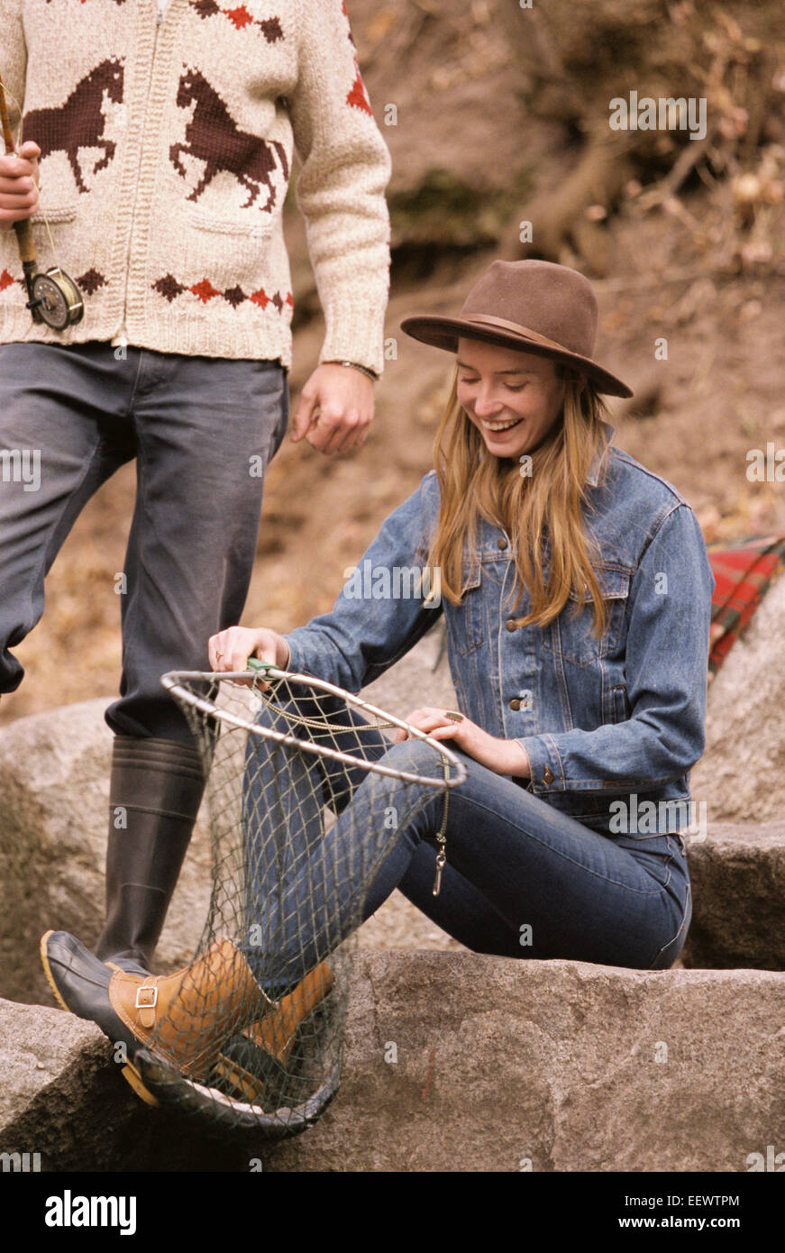 Coppia giovane in una foresta, pesca in un fiume, donna sorridente tenendo un pesce in un net. Foto Stock