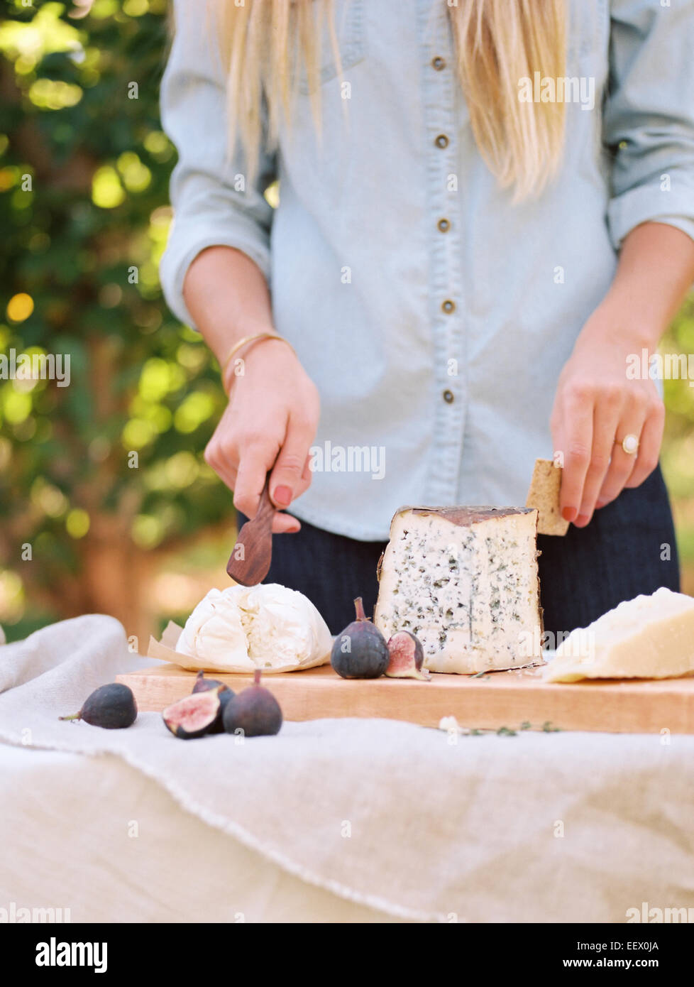 La donna a un tavolo con il cibo, un formaggio a bordo. Foto Stock