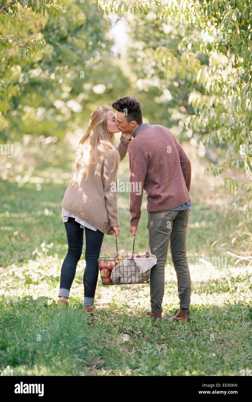 Matura portante un cesto di mele, baciare. Foto Stock