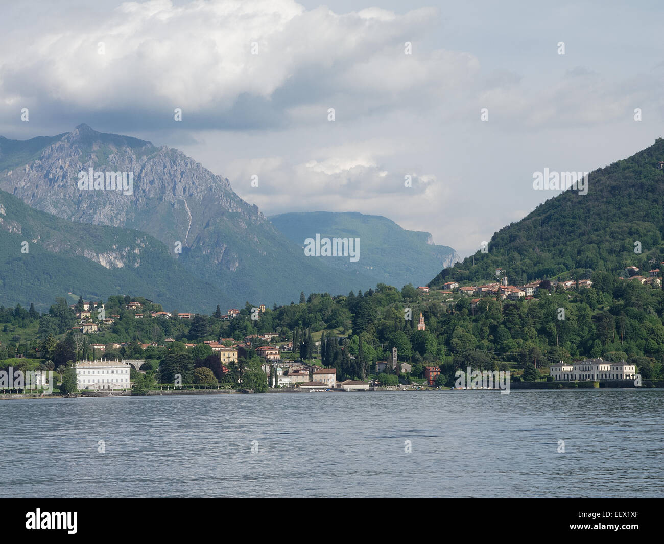 Bellagio sul Lago di Como in Italia prendere il sole di inizio estate con un albero fiancheggiato da montagne sullo sfondo Foto Stock