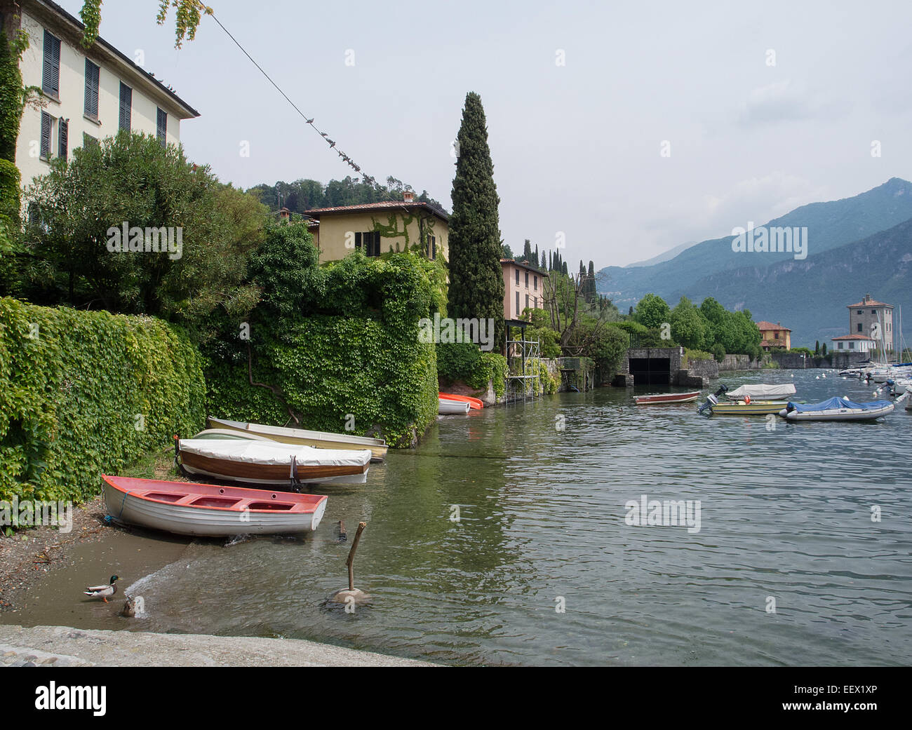 Il paese di Pascallo sul lago di Como in Italia con piccole barche in primo piano e uno sfondo di montagne Foto Stock
