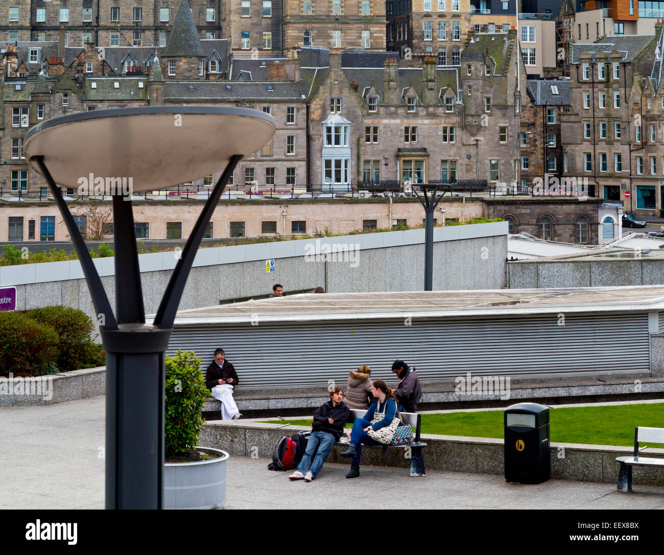 La gente seduta sulle panchine in centro città vicino a Princes Street Edinburgh Scotland Regno Unito con la Città Vecchia in background Foto Stock
