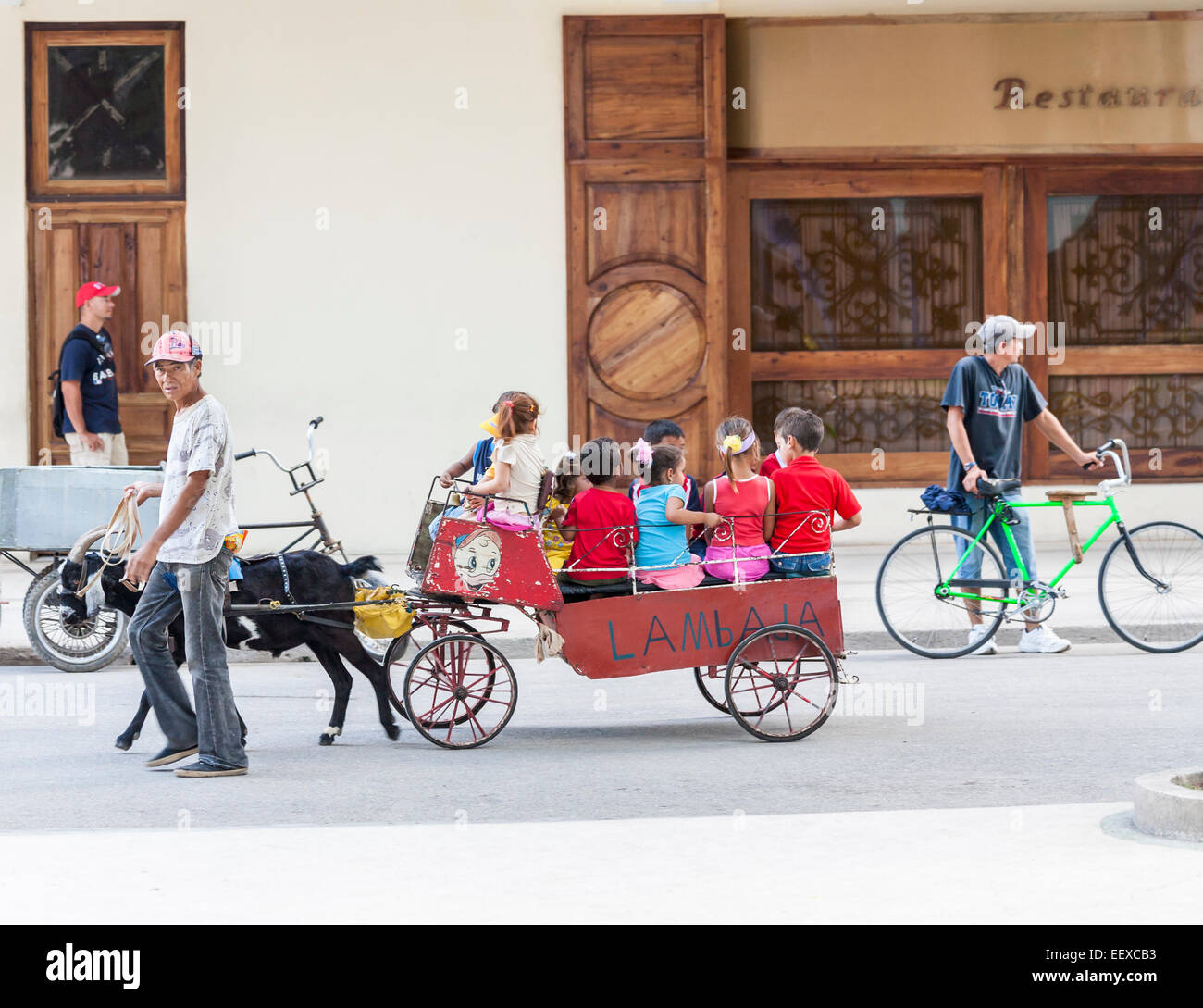 Un gruppo di giovani i bambini in un carro trainato da una capra in una strada a Camaguey, Cuba è la terza città più grande Foto Stock