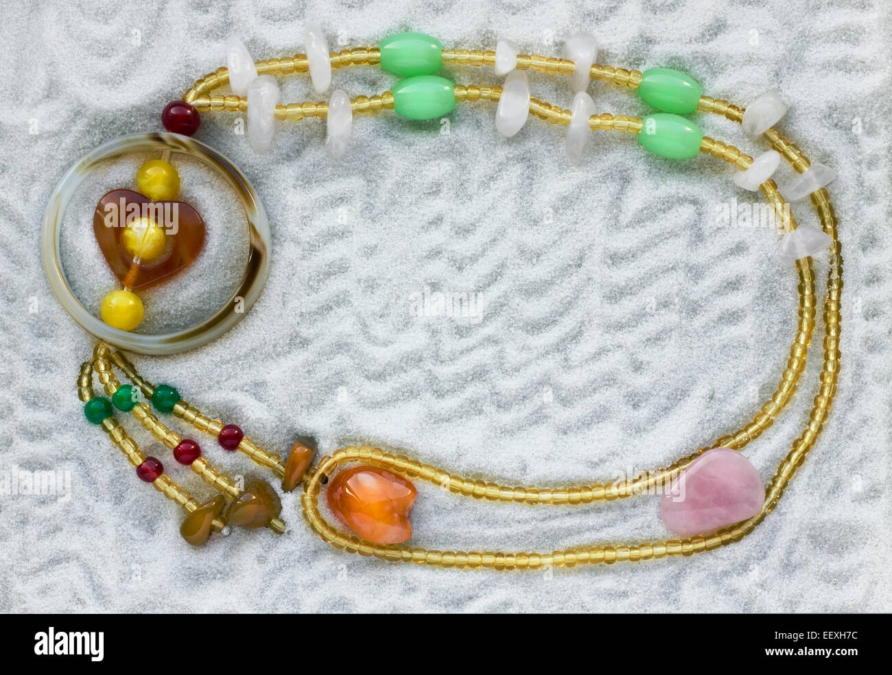 La collana dal vetro colorato talloni giace sul puro bianco sabbia di mare. Sfondo di macro Foto Stock