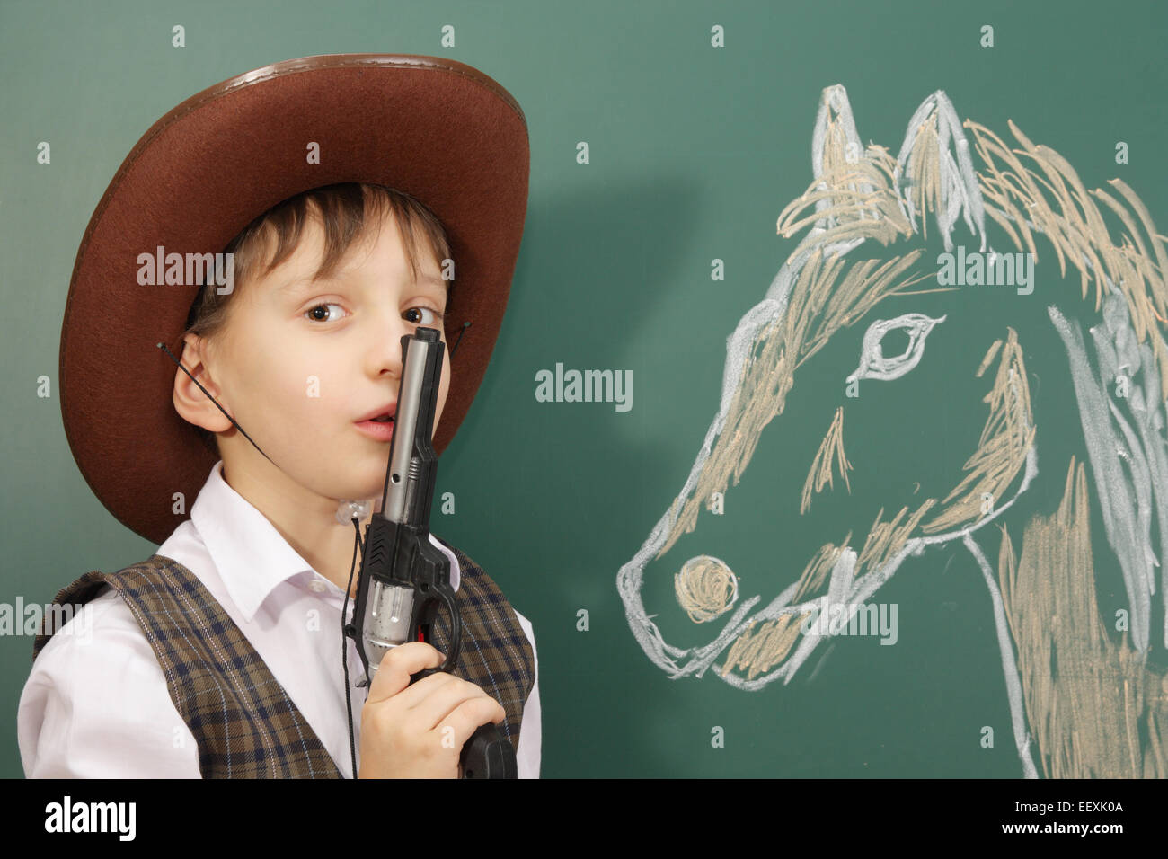 Felice piccolo ragazzo con pistola e il suo cavallo Foto Stock