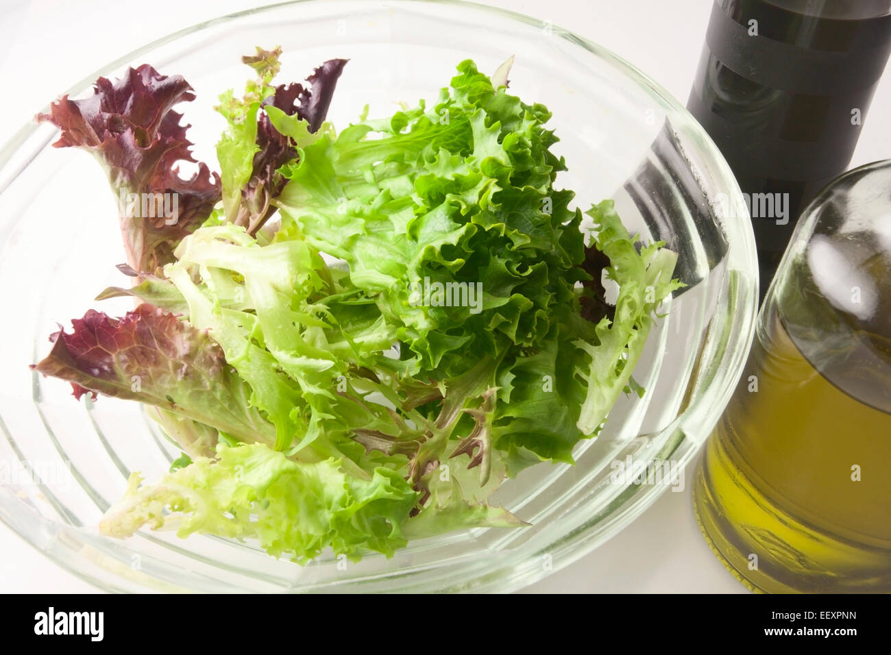 Miscelati rosso e verde lattuga multilamina foglie in una ciotola di vetro con olio extra vergine di oliva e aceto balsamico Foto Stock