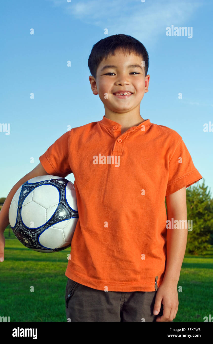 Giovane ragazzo al parco con un pallone da calcio Foto Stock