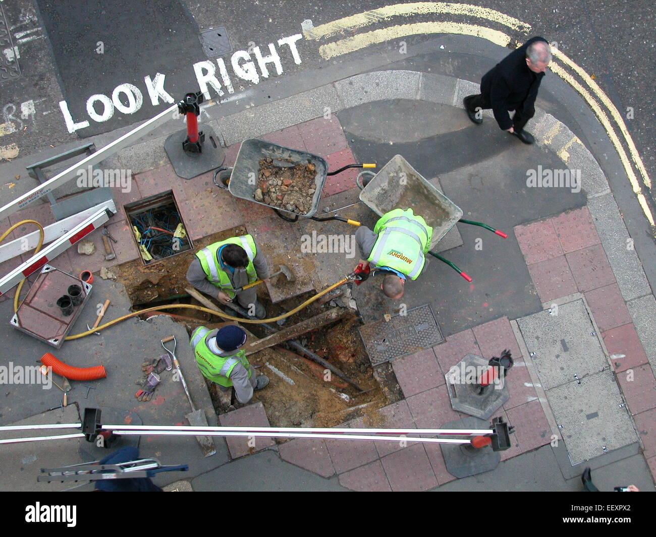 La posa di cavi sotto la pavimentazione cavo Murphy strati operai scavo pavimentazione stradale disturbi la London Street Foto Stock