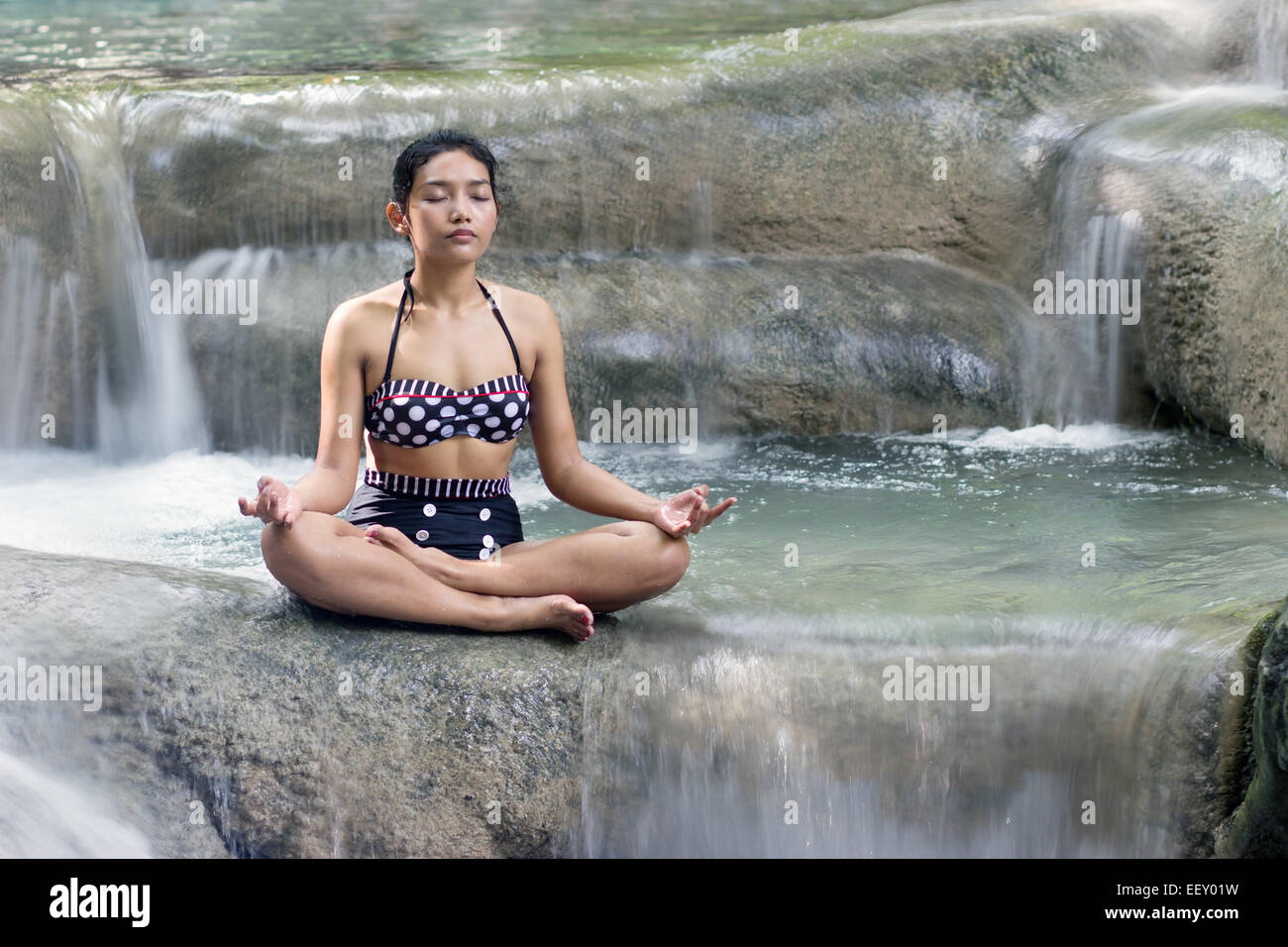 Donna in costume da bagno retrò fare yoga in cascata Foto Stock