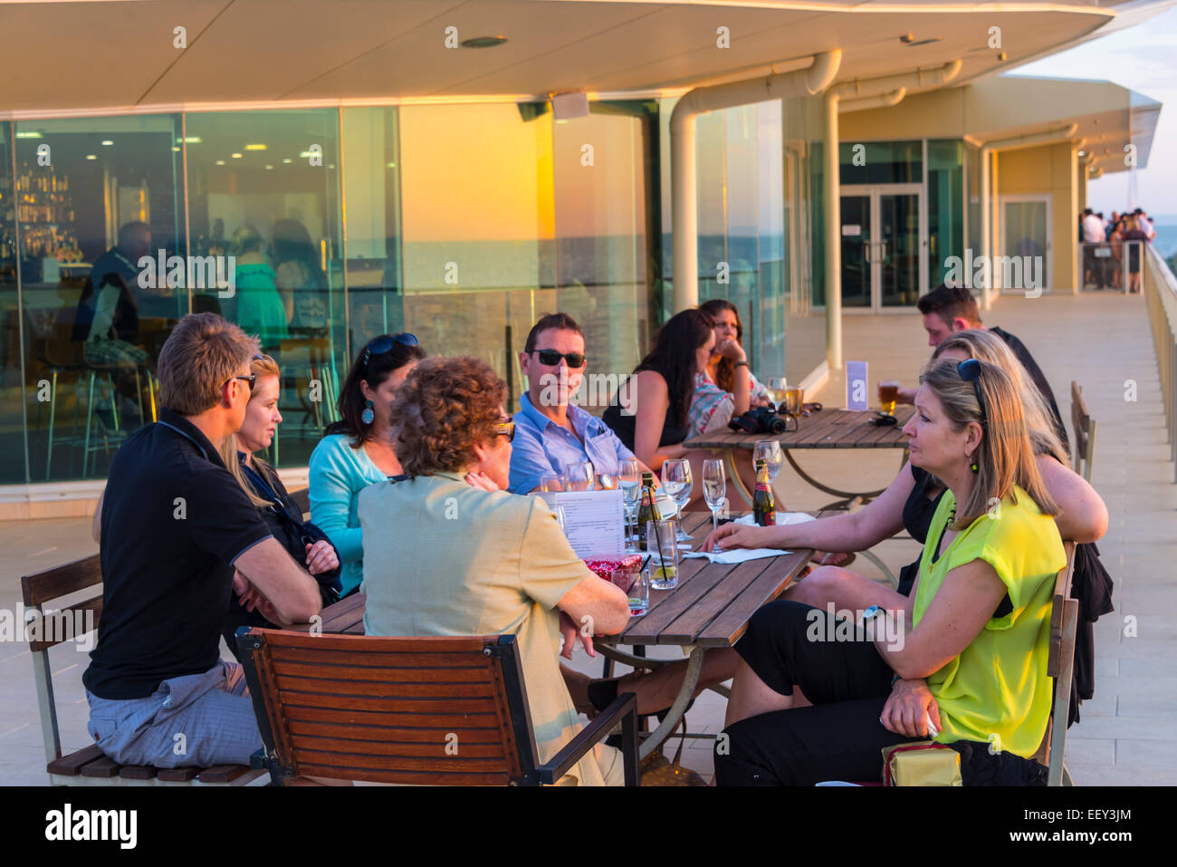 Riunione di famiglia sociale giovani adulti con la madre esterna di estate impostazione mangiare bere celebrando godendo di una serata estiva sunset Foto Stock