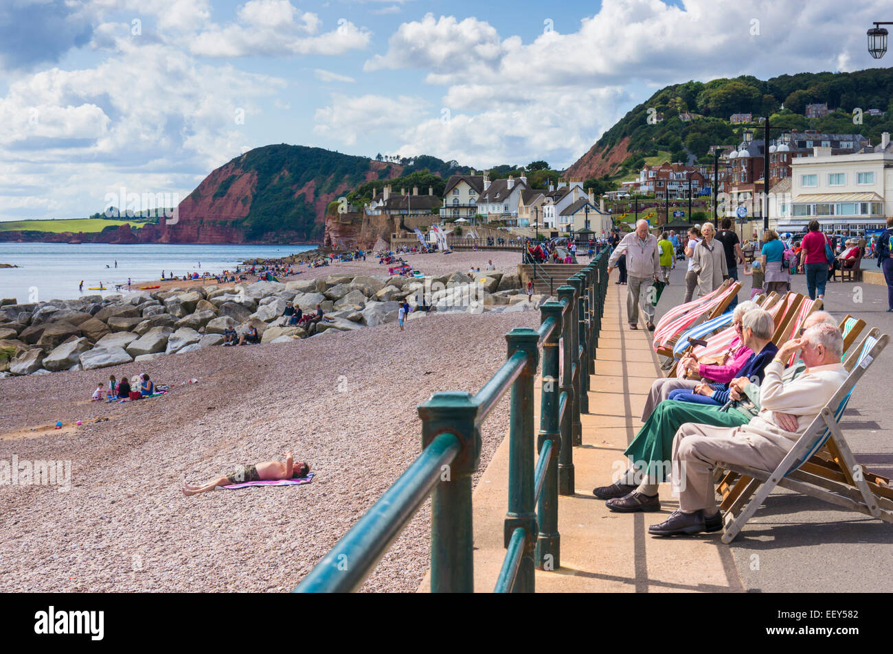 Persone sedute in sedie a sdraio sul lungomare a Sidmouth, East Devon, Inghilterra, Regno Unito Foto Stock