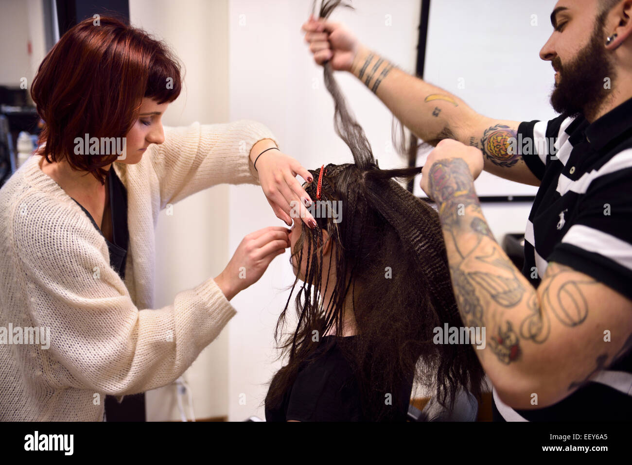 Studente parrucchiere e truccatore lavora sui capelli e il volto di un modello in un salone Foto Stock