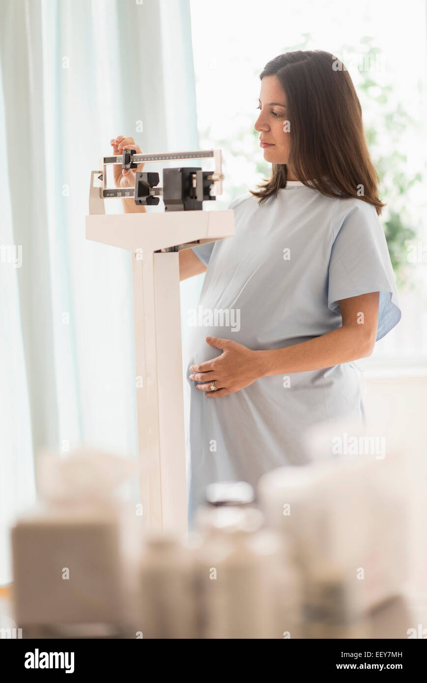 Donna incinta in ufficio medici in piedi sulla scala Foto Stock