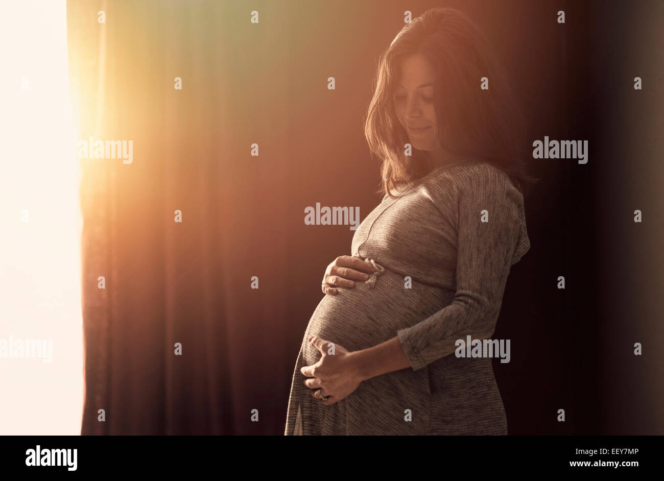 Donna incinta toccando ventre a casa Foto Stock