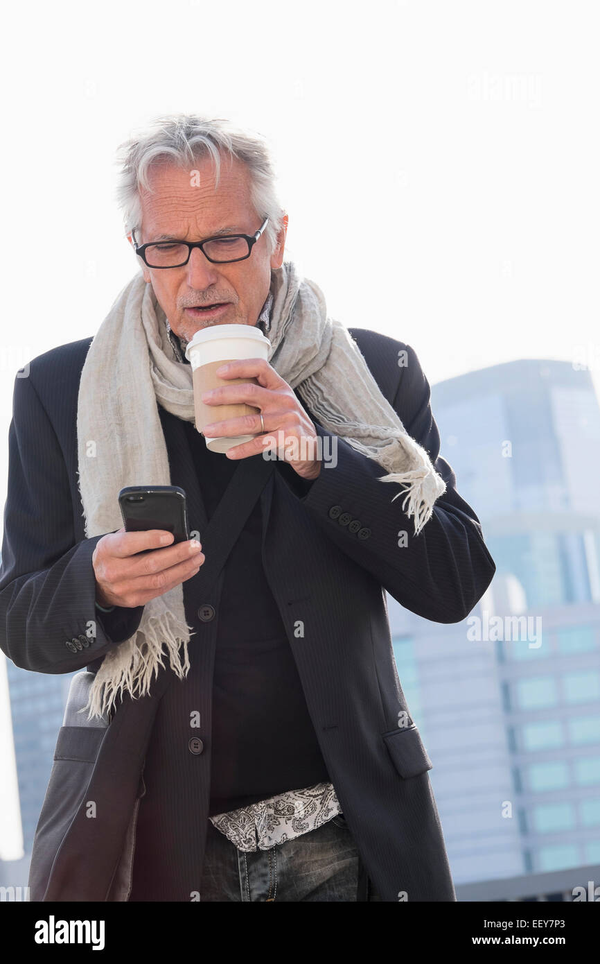 Uomo in strada a bere caffè utilizza lo smartphone Foto Stock