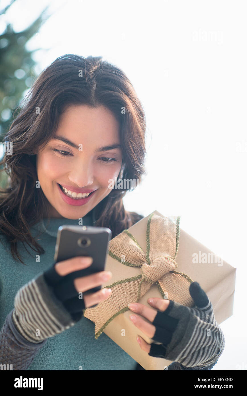 Sorridente giovane donna azienda dono e messaggistica di testo Foto Stock