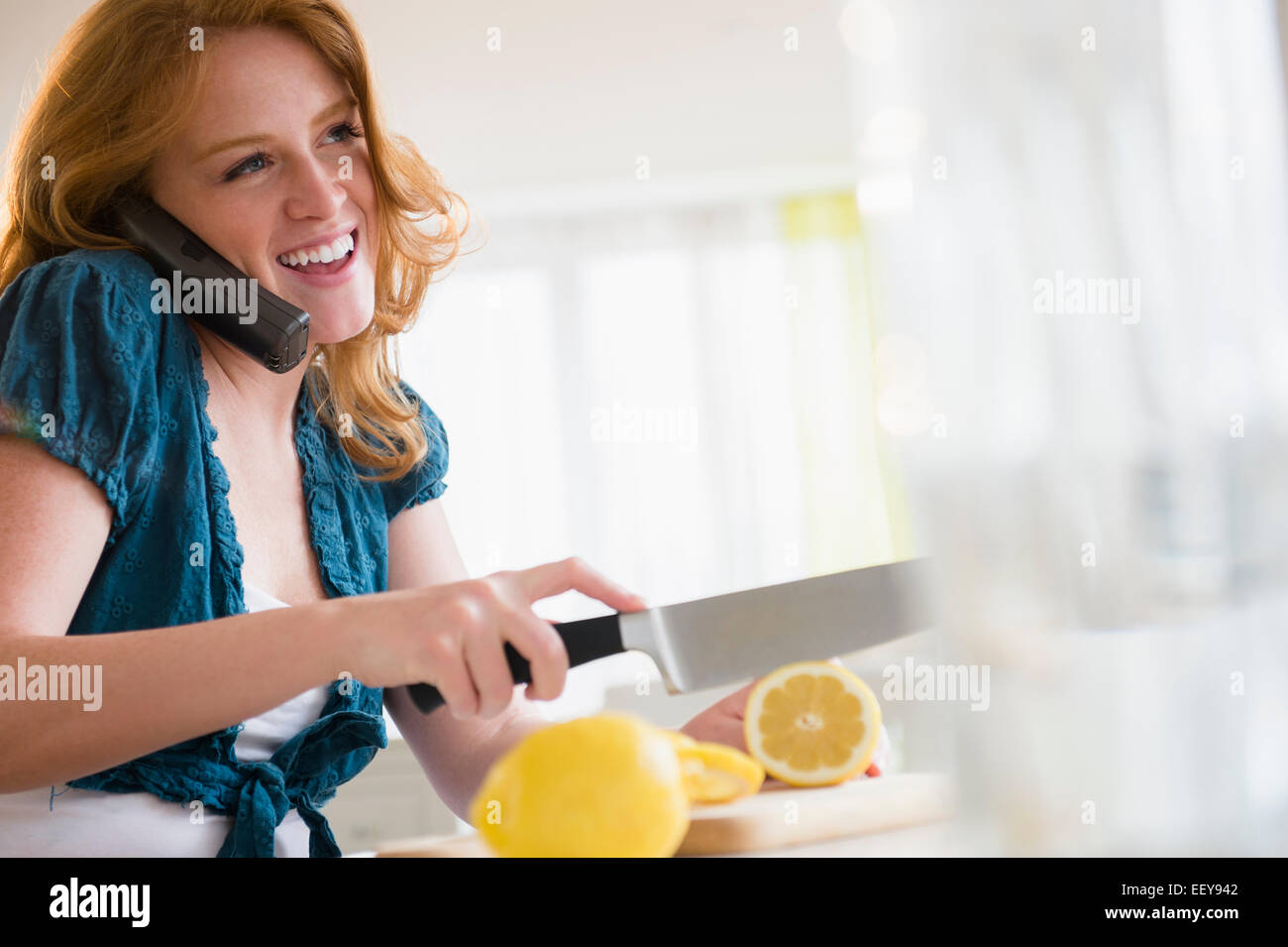 Giovane donna il taglio di limone e parlando al telefono Foto Stock