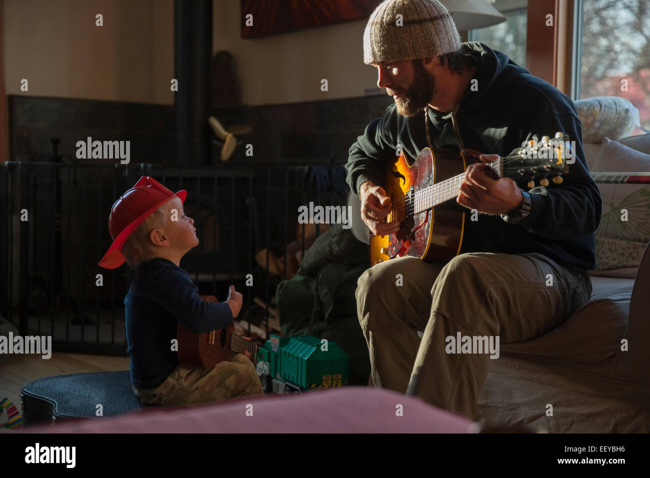 Ragazzo (4-5) Ascoltando il suo papà a suonare la chitarra Foto Stock