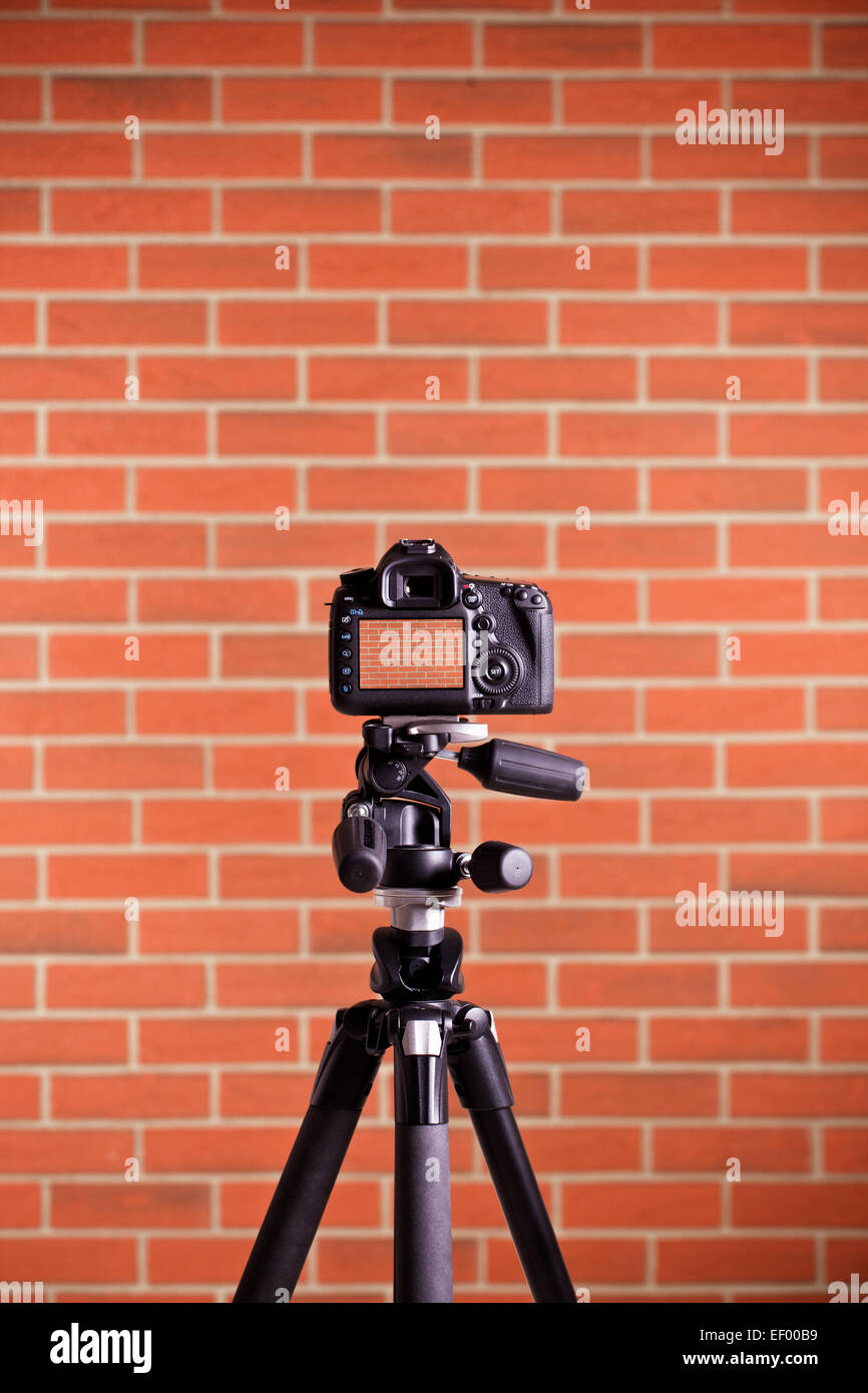 La fotocamera reflex digitale su un cavalletto di ripresa la parete in mattoni Foto Stock