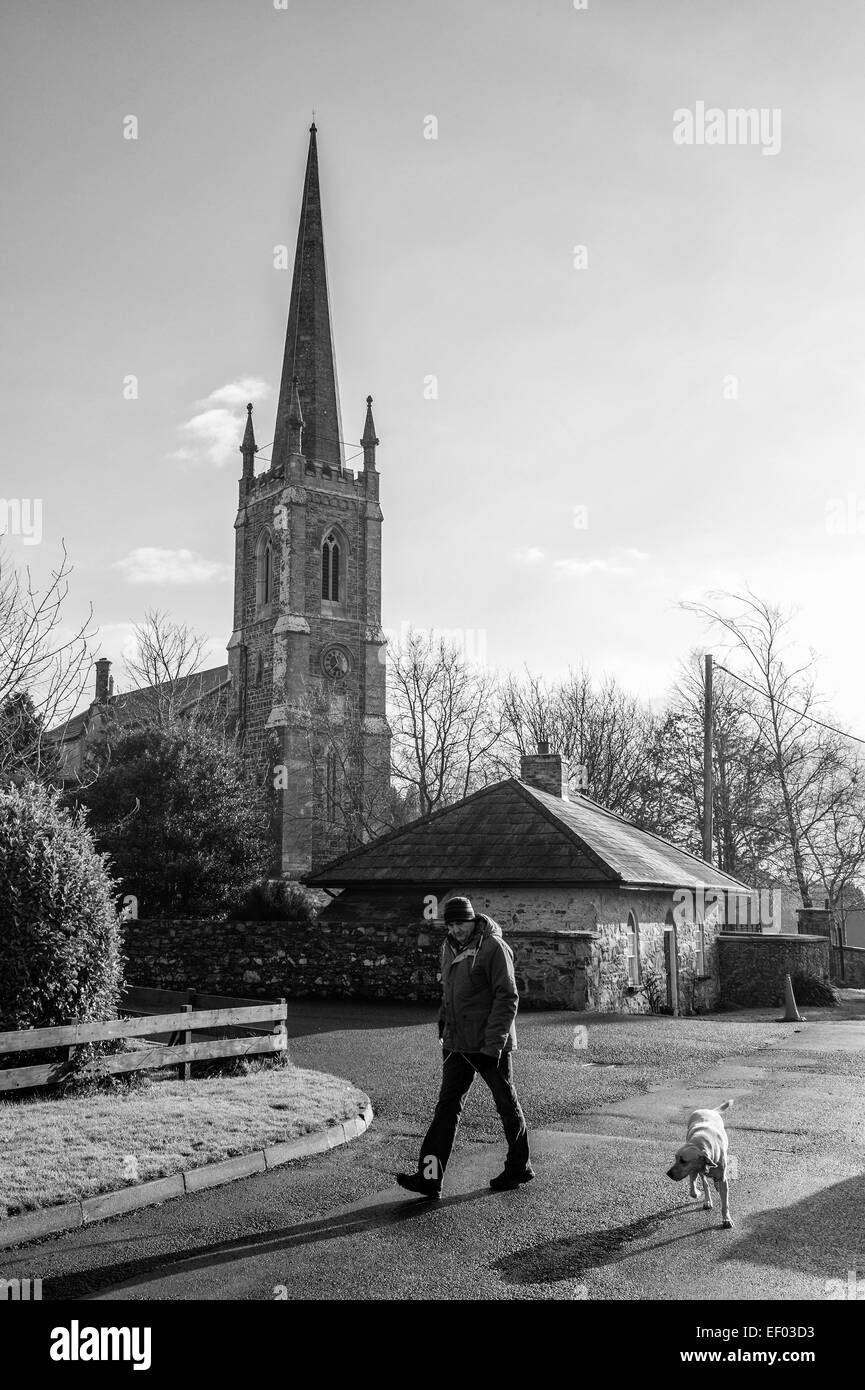 Uomo che cammina il suo cane con Kilmood Chiesa Parrocchiale in background. Foto Stock