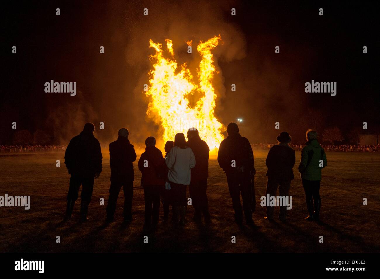Stagliano persone stare a guardare un falò organizzati nel Parco Bught, Inverness, Highlands. Le fiamme raggiungono elevate. Foto Stock