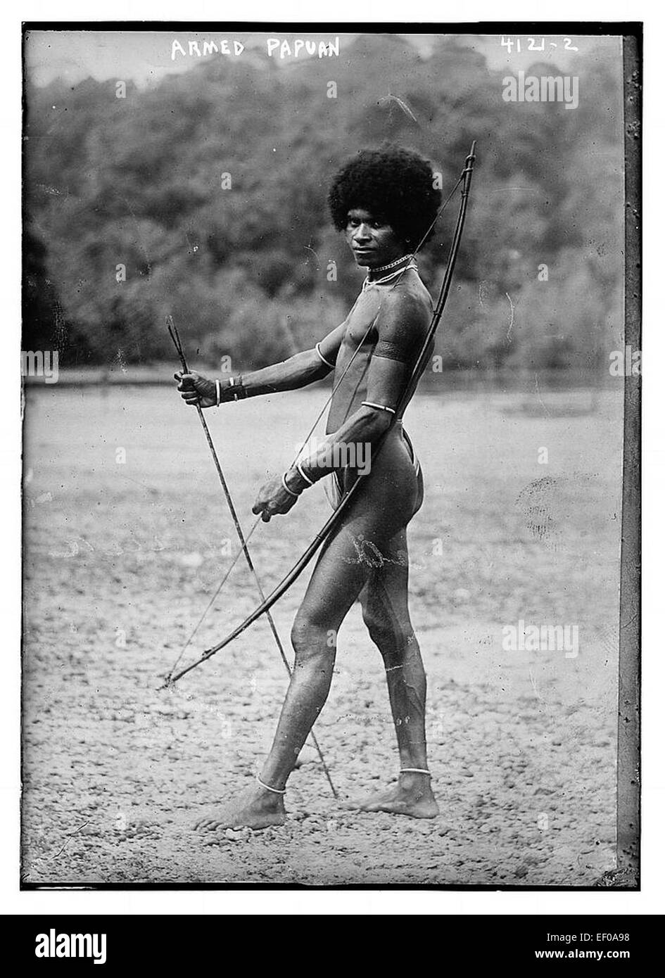 Questa immagine raffigura un uomo armato di Papua nuova Guinea, probabilmente proveniente dalle regioni montuose della Papua nuova Guinea. È un riflesso delle culture tradizionali in cui le armi e l'abbigliamento giocano un ruolo nell'identità. Foto Stock