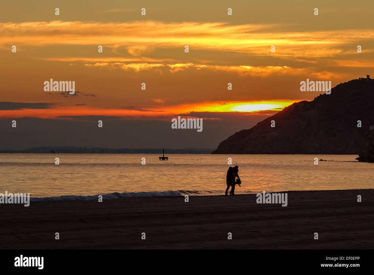 Benidorm tramonto arancione con il mare, la sabbia, sagome e nuvole Foto Stock