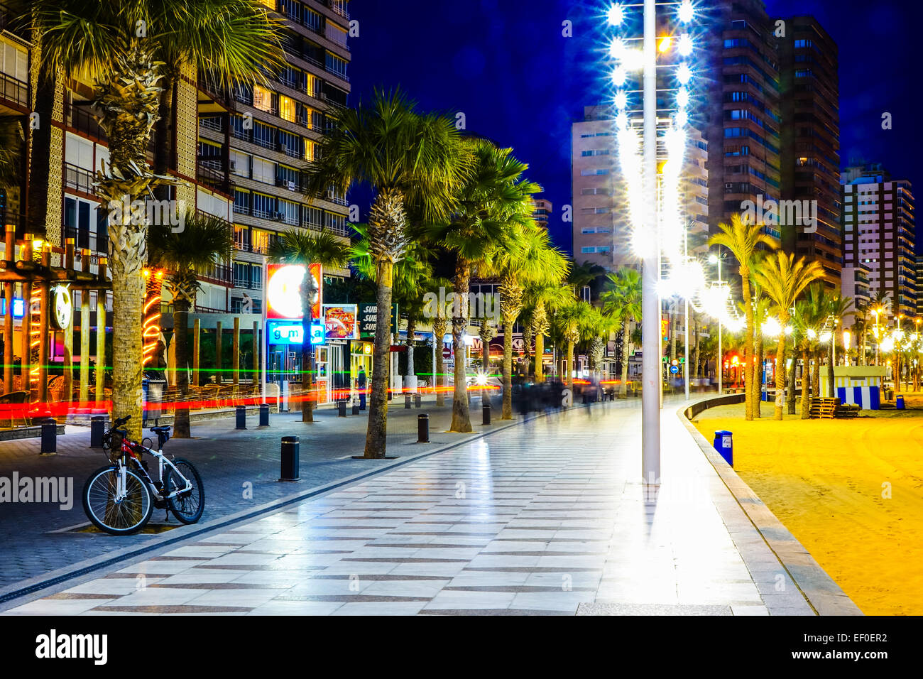 Benidorm promenade , fiancheggiata da palme di notte e la spiaggia Foto Stock