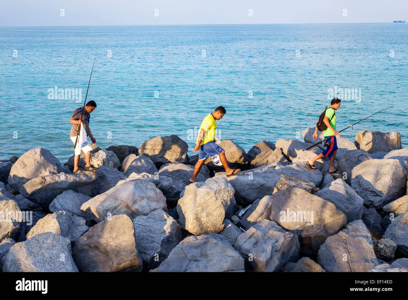 Miami Beach Florida,Oceano Atlantico,molo di roccia,frangiflutti,latini ispanici asiatici,uomo maschio,amici,arrampicata su,pesca in corso,canne,pali,FL14110701 Foto Stock