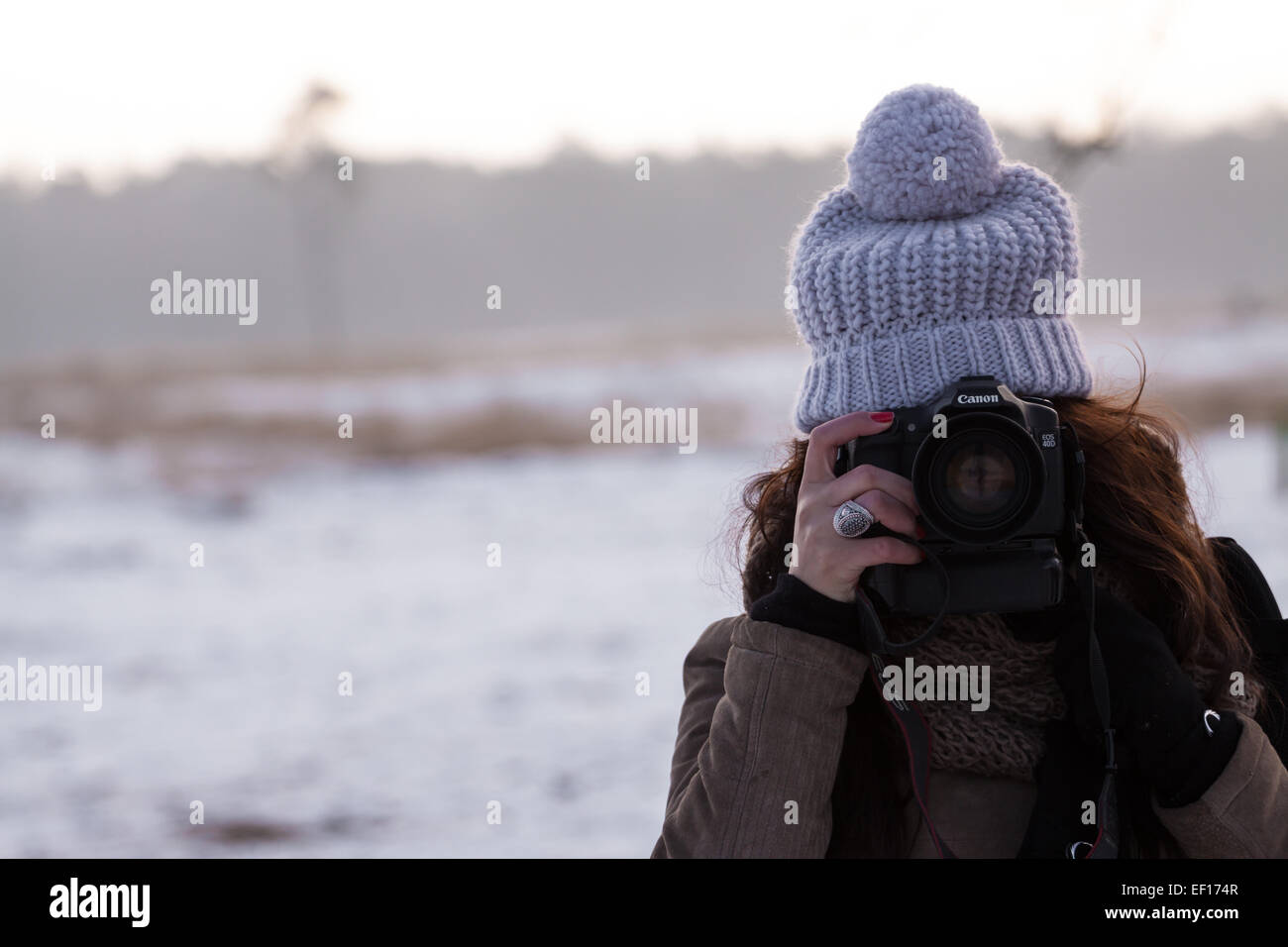 Ragazza che indossa un cappello e scattare una foto al parco nazionale di Loonse en Drunense Duinen con un paesaggio di neve in background Foto Stock