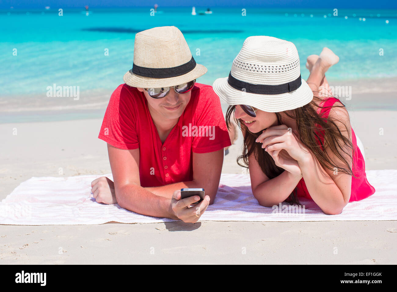 Felice coppia giovane con un telefono cellulare sulla tropicale spiaggia bianca Foto Stock