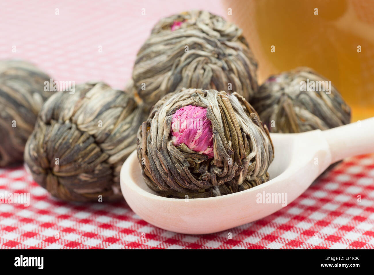 Il tè verde sfere con fiori, tazza da tè e il cucchiaio di legno sul tavolo da cucina Foto Stock
