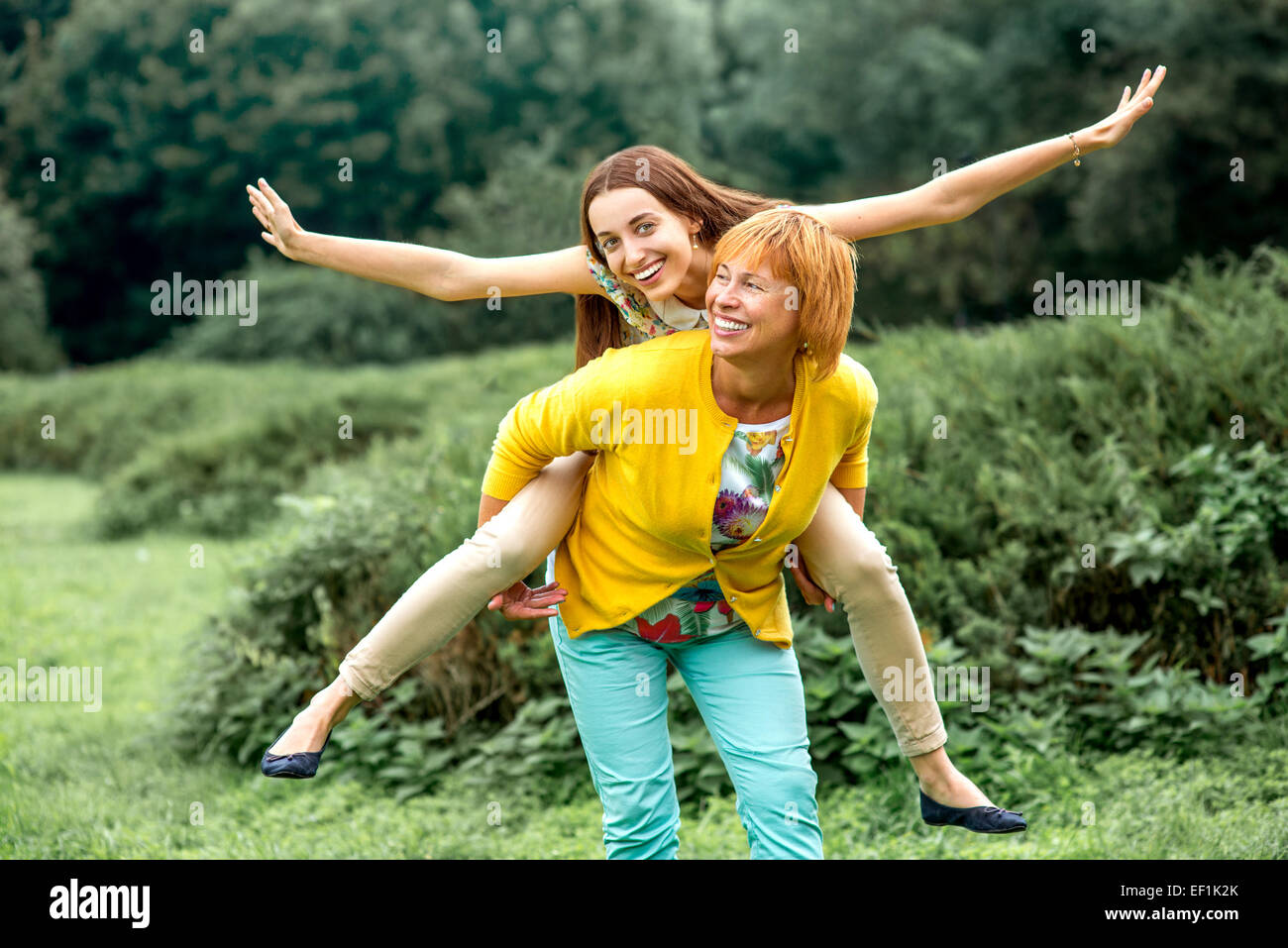 Madre dando sovrapponibile in sella alla sua figlia nel parco Foto Stock