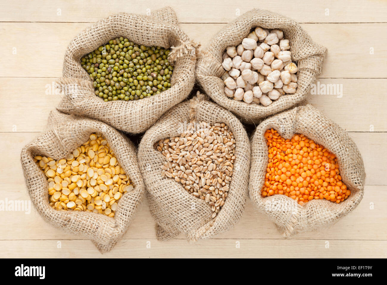Sacchetti di Hesse con grani di cereale: di lenticchie rosse, piselli, ceci, frumento e verde mung sul tavolo di legno, vista dall'alto Foto Stock