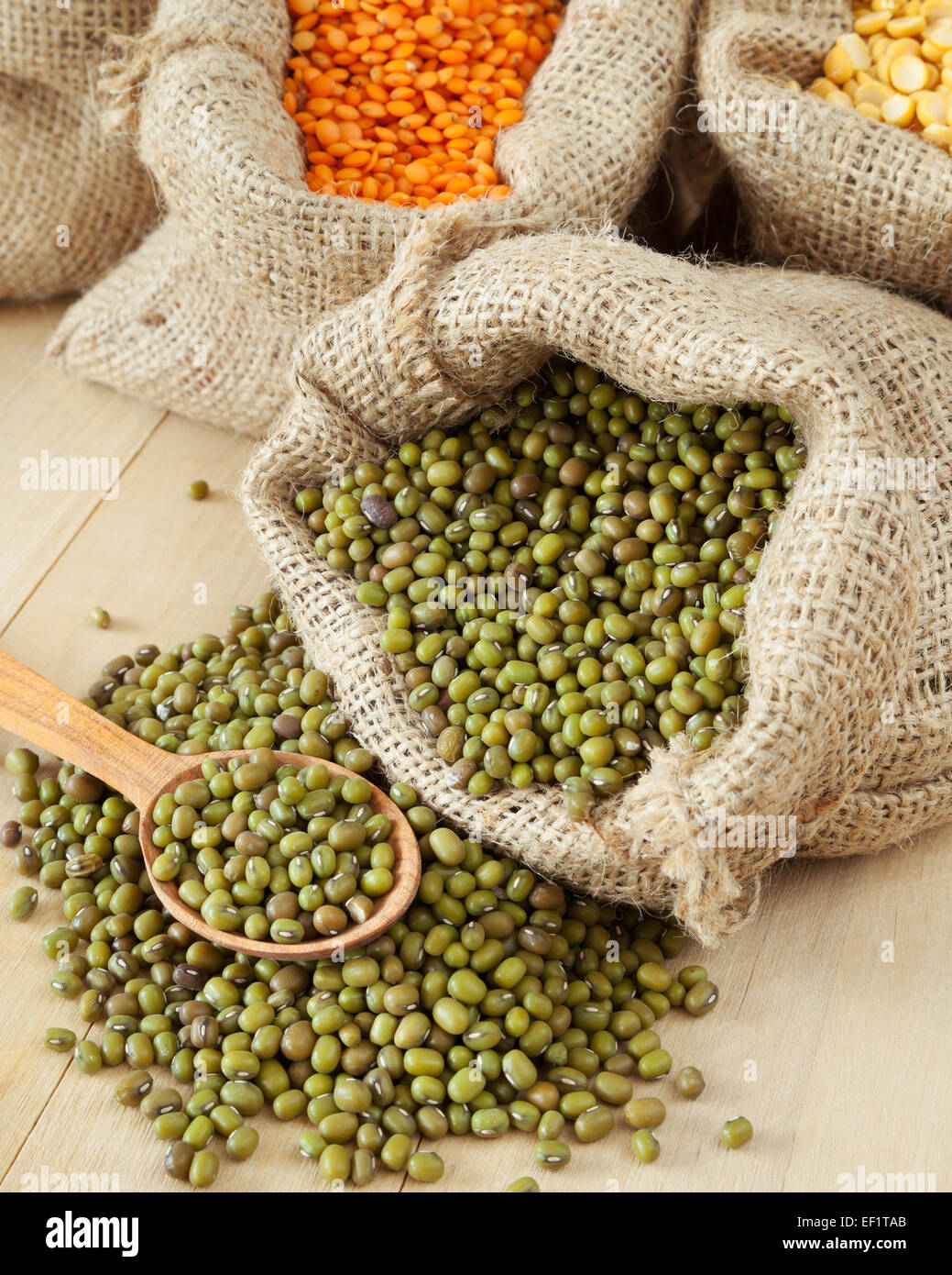 Sacchetti di Hesse con grani di cereale: verde mung closeup, di lenticchie rosse e piselli sul tavolo di legno Foto Stock