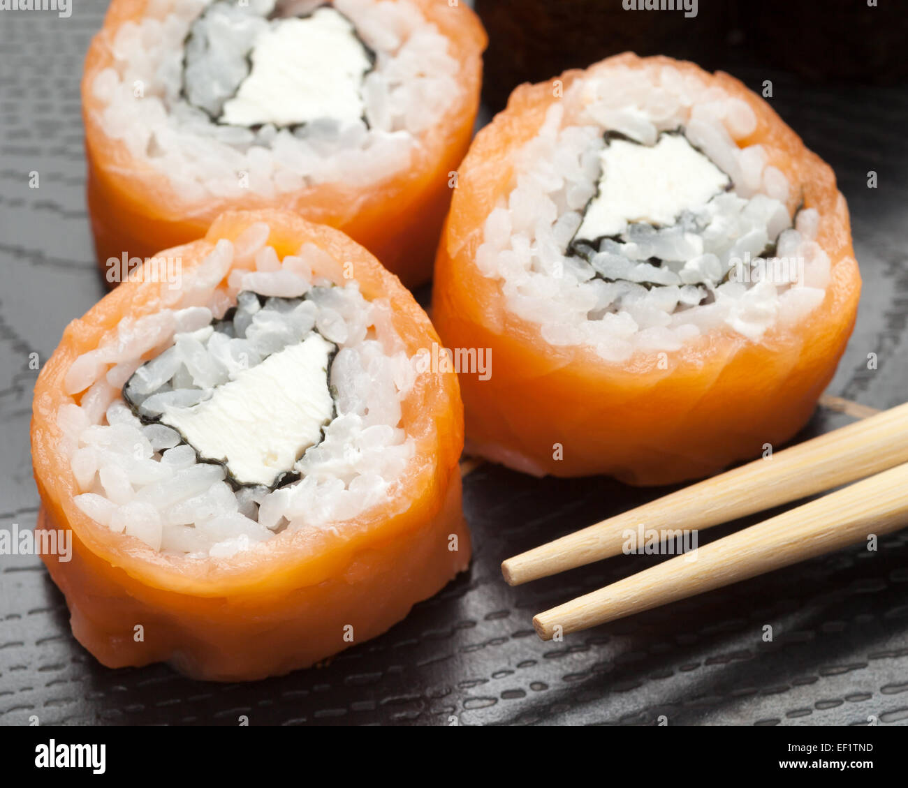 Il sushi fatto di salmone affumicato e formaggio Filadelfia con bacchette Foto Stock