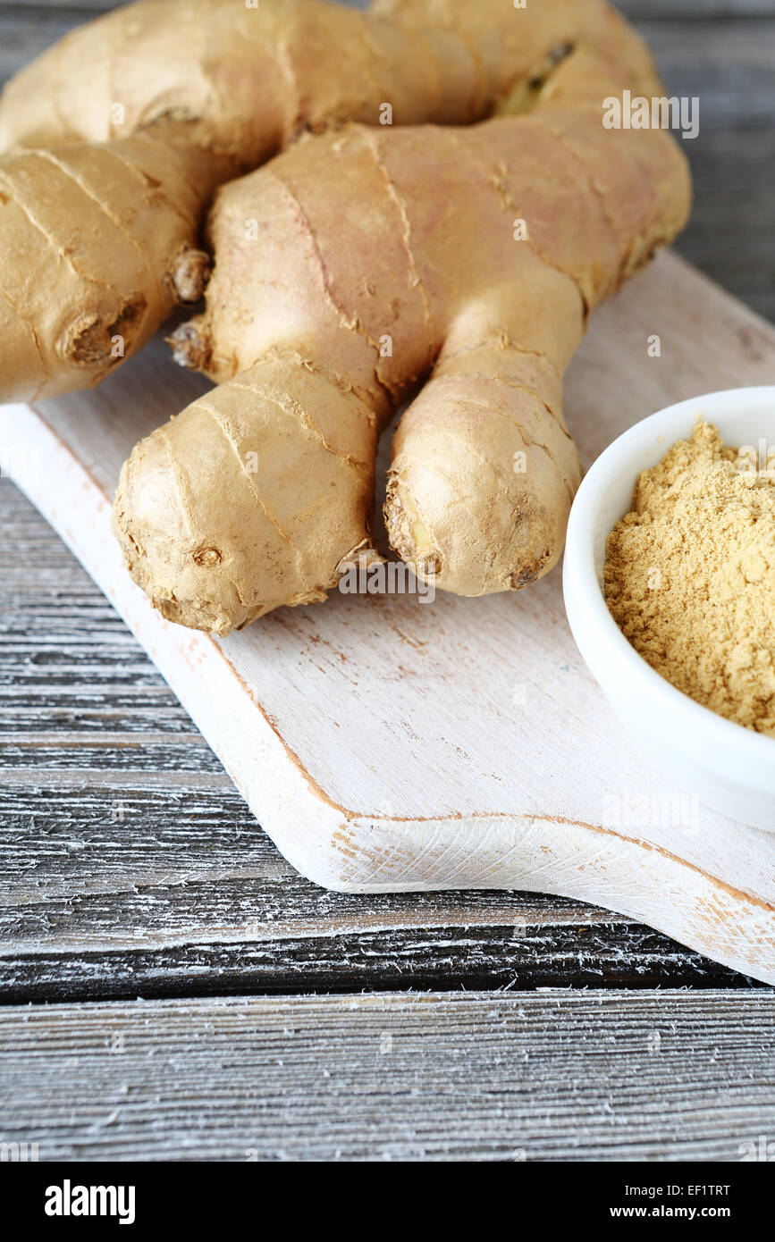 Zenzero fresco, sullo sfondo di legno Foto Stock
