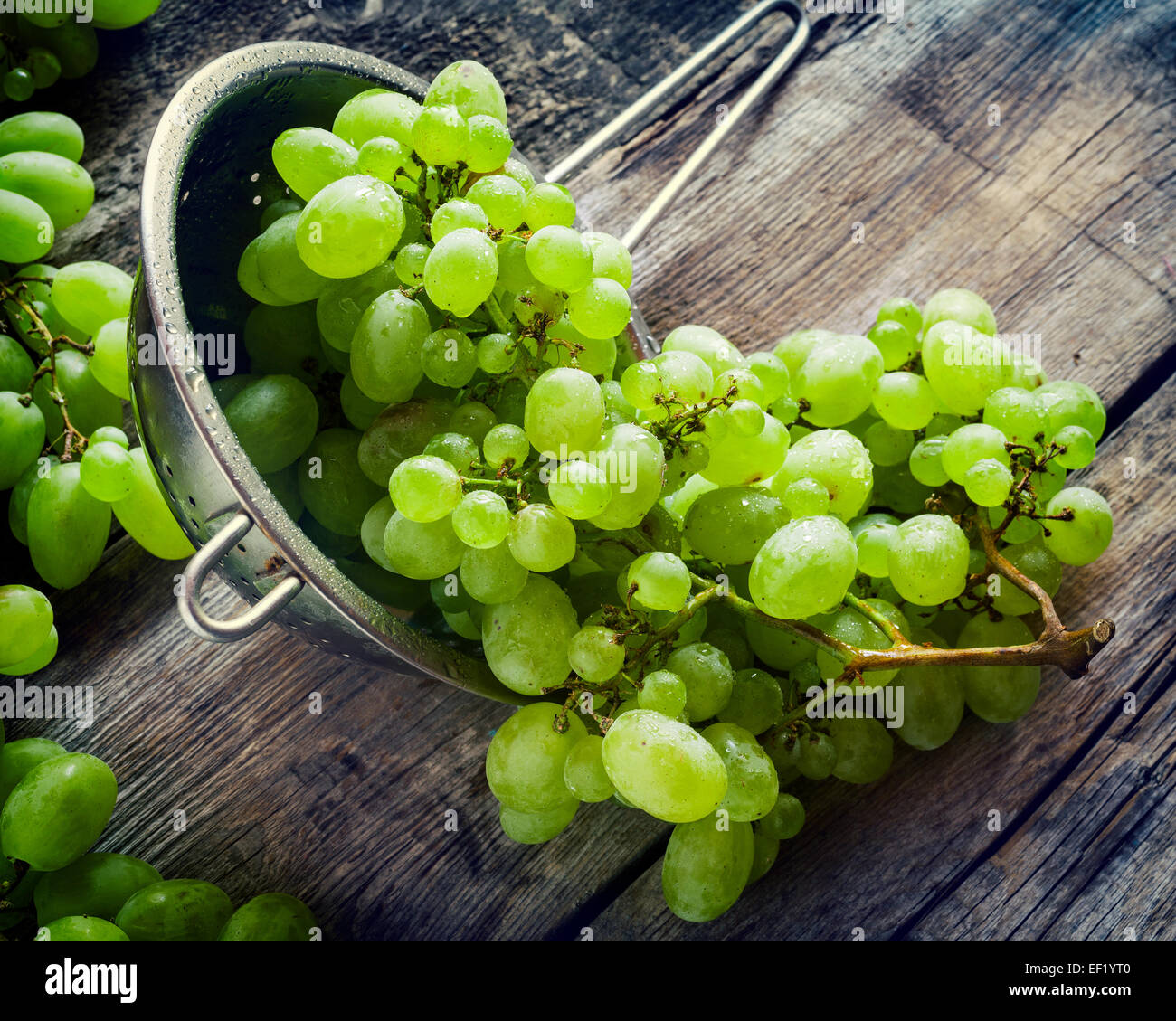 Le uve in metallo scolapasta su legno tavolo rustico, vintage stilizzata Foto Stock