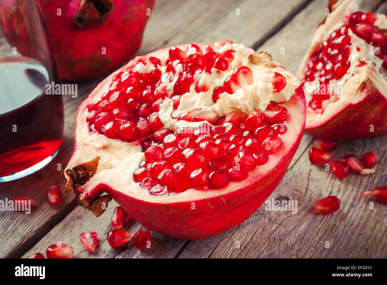 Pezzi di ripe melograno e succhi di frutta in vetro su legno tavolo rustico Foto Stock