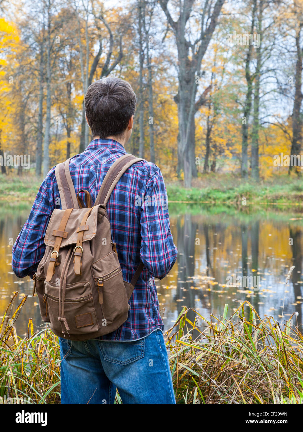Giovane maschio escursionista sostare vicino lago d'autunno Foto Stock