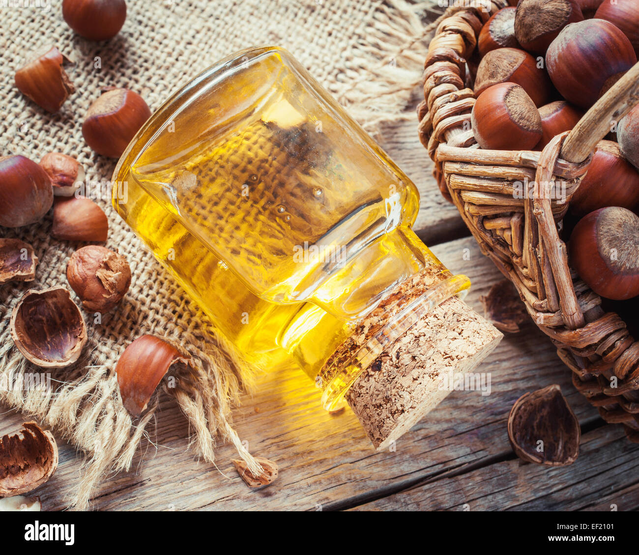 Bottiglia di olio di noci e il cestello con nocciole sul vecchio tavolo da cucina. Vista dall'alto. Foto Stock